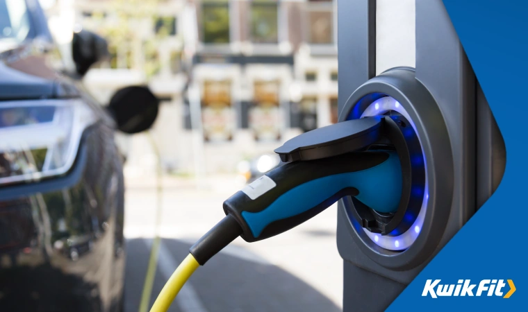 A modern electric car plugged in to charge at the curbside.