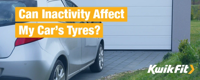 A silver car sat on a driveway in front of a garage.