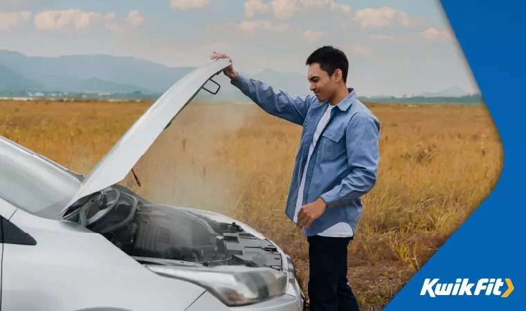 A driver opens the bonnet of their car. Its engine smokes after having overheated on a severely hot day.