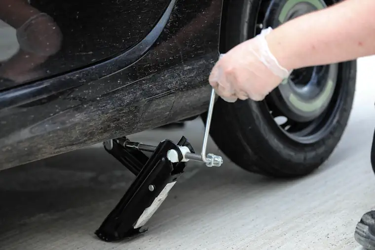 Person lowering a car with a jack.