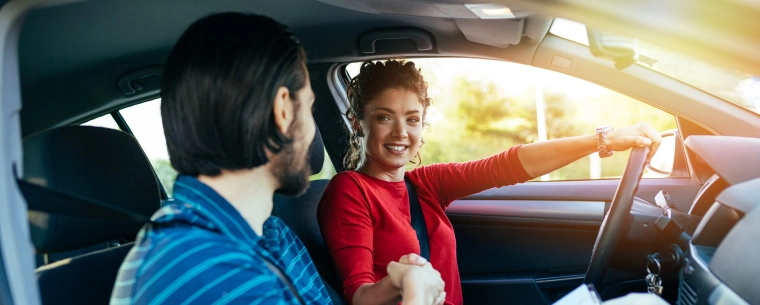 Woman sitting in the drivers seat shaking the instructors hand after passing her driving test