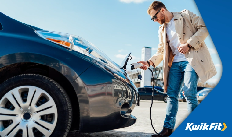 Person connecting an electric charger to the charging port of a vehicle which is located underneath the bonnet.